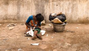 Como acabar com a fome no mundo. Imagem de uma mulher sentada no chão, vivendo na miséria.